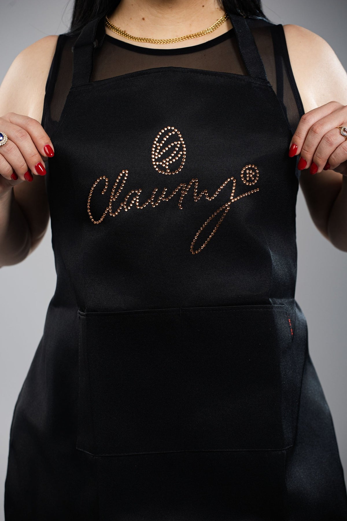Detalle real del delantal negro Claumy® con logotipo de pedrería